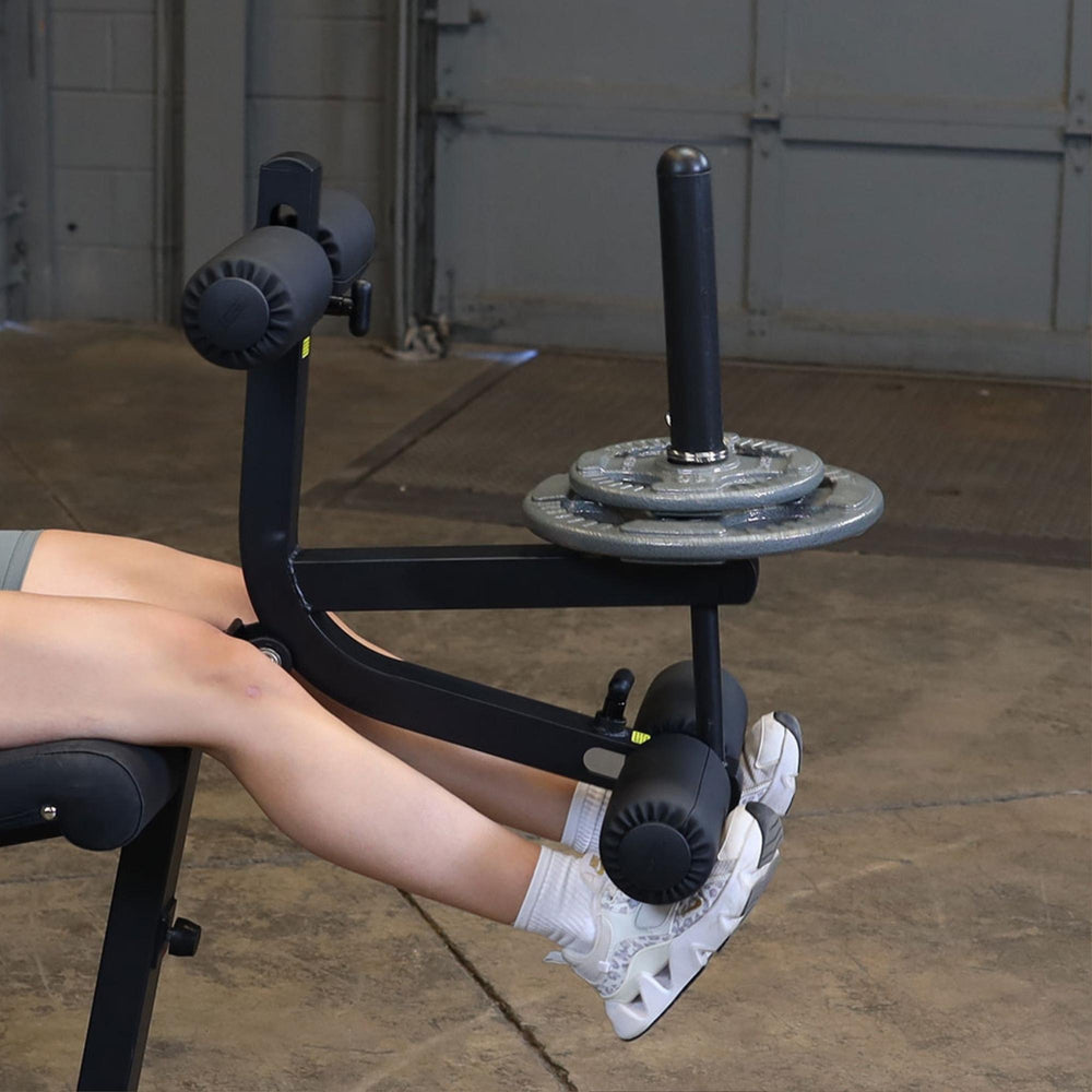 Body-Solid Seated Leg Extension & Supine Curl GLCE365B Leg extension exercise with multiple weight plates attached