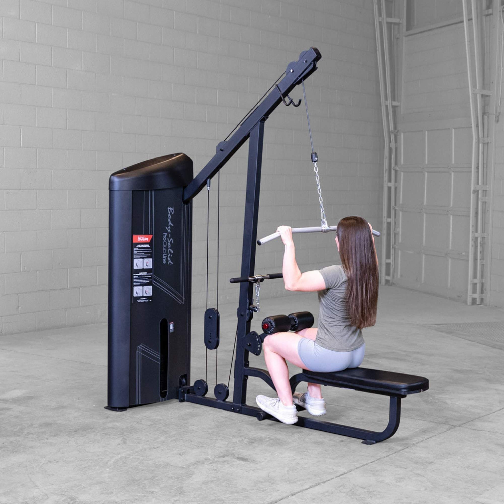 Body-Solid Series 2 Lat Mid Row S2LATX  Rear view of woman using Body-Solid ProClub Line lat pulldown machine pulling wide-grip bar toward her shoulders