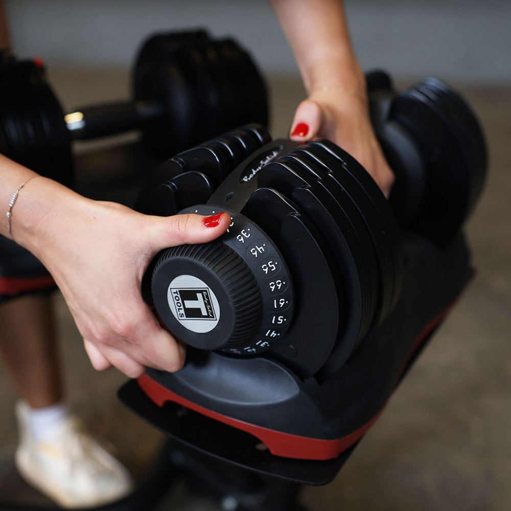 Body-Solid Tools Adjustable Dumbbell Set, 11 lb. to 66 lb. with Stand SDBX132ST Close-up of hands adjusting the weight setting