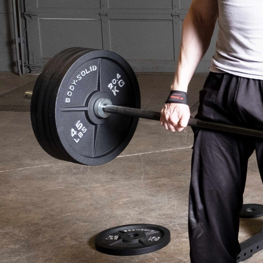 Body-Solid Tools Cast Iron 2" Olympic Plates OSB255 Close-up of athlete lifting barbell loaded with Body-Solid 45 lb Olympic weight plates during strength training.