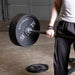 Body-Solid Tools Cast Iron 2" Olympic Plates OSB255 Close-up of athlete lifting barbell loaded with Body-Solid 45 lb Olympic weight plates during strength training.