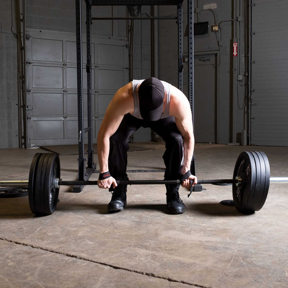 Body-Solid Tools Cast Iron 2" Olympic Plates OSB255 Man preparing for a deadlift using a barbell with multiple Body-Solid Olympic plates in an industrial-style gym.