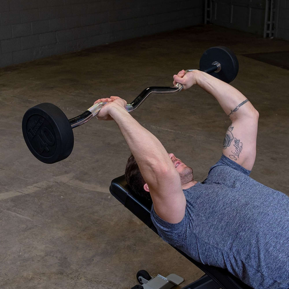 Body-Solid Tools Fixed Weight EZ Curl Barbells, from 20 to 110 lb. Man executing skull crushers on incline bench using EZ curl bar for tricep development