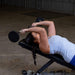 Body-Solid Tools Fixed Weight EZ Curl Barbells, from 20 to 110 lb. Woman performing incline skull crushers with 20 lb EZ curl bar on adjustable bench