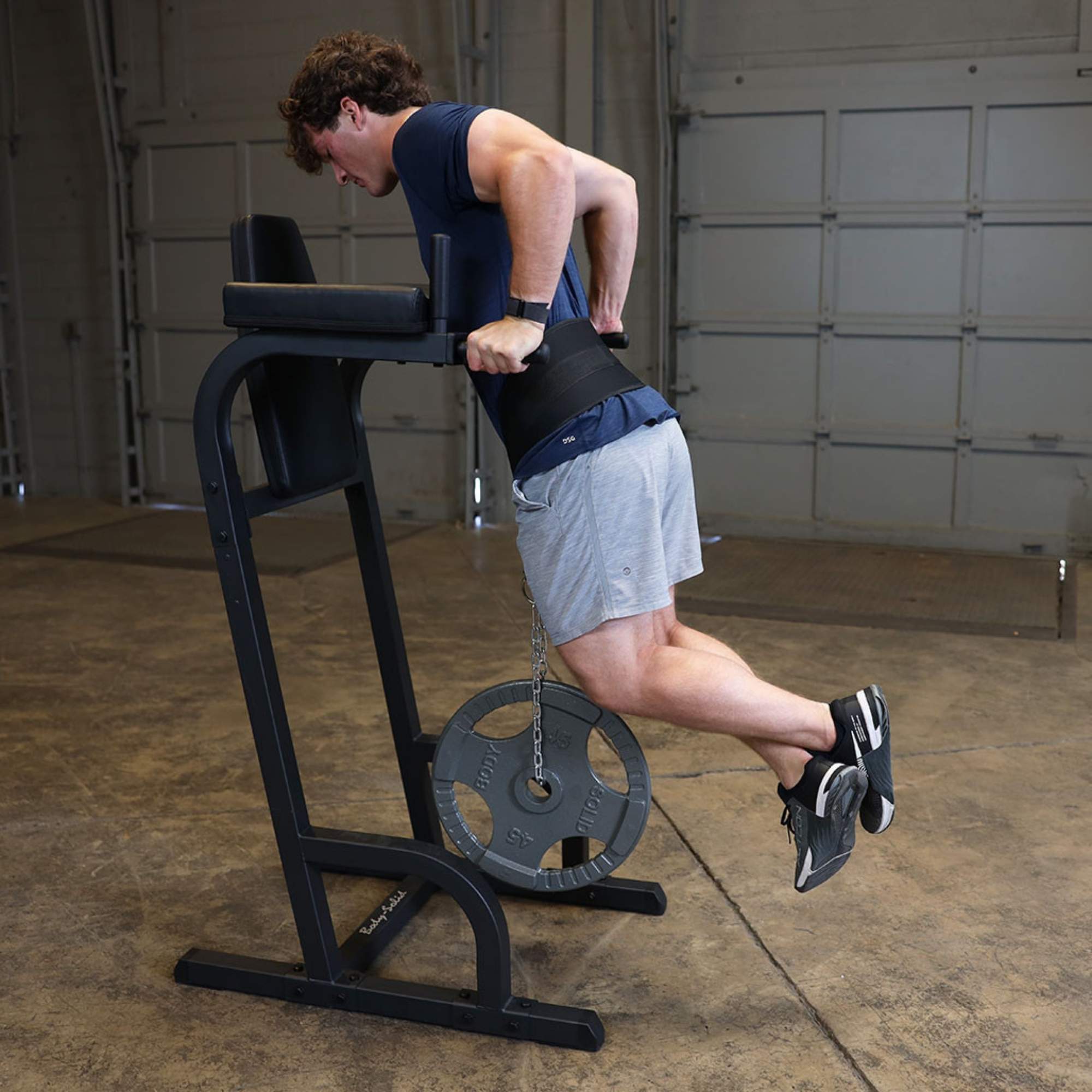 Body-Solid Vertical Knee Raise and Dip GVKR60B Man performing weighted dips using a Body-Solid VKR station and a dip belt with weight plates