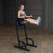 Body-Solid Vertical Knee Raise and Dip GVKR60B Woman lifting her legs straight out while using the Body-Solid VKR station for core training