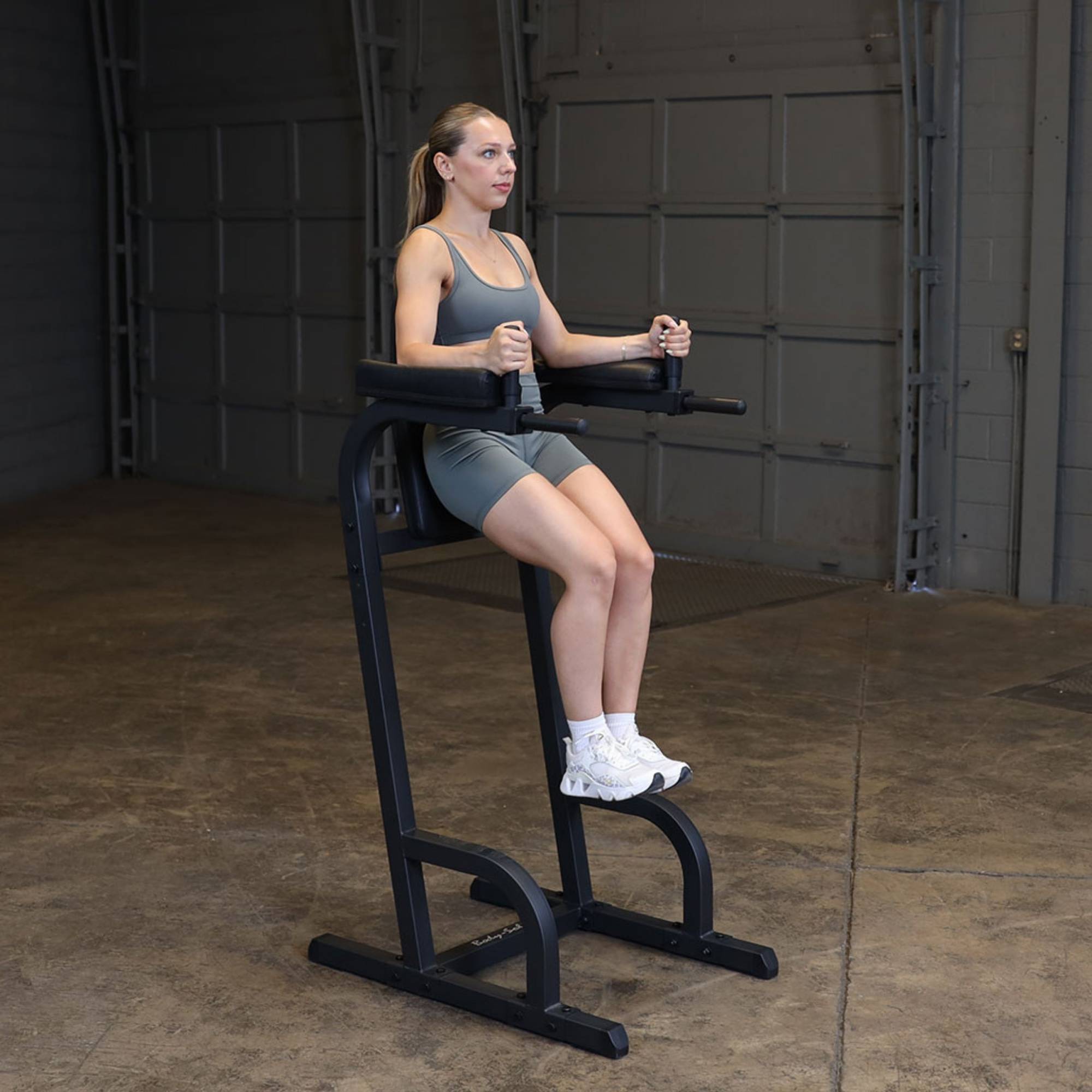 Body-Solid Vertical Knee Raise and Dip GVKR60B Woman seated in resting position on the Body-Solid vertical knee raise and dip station