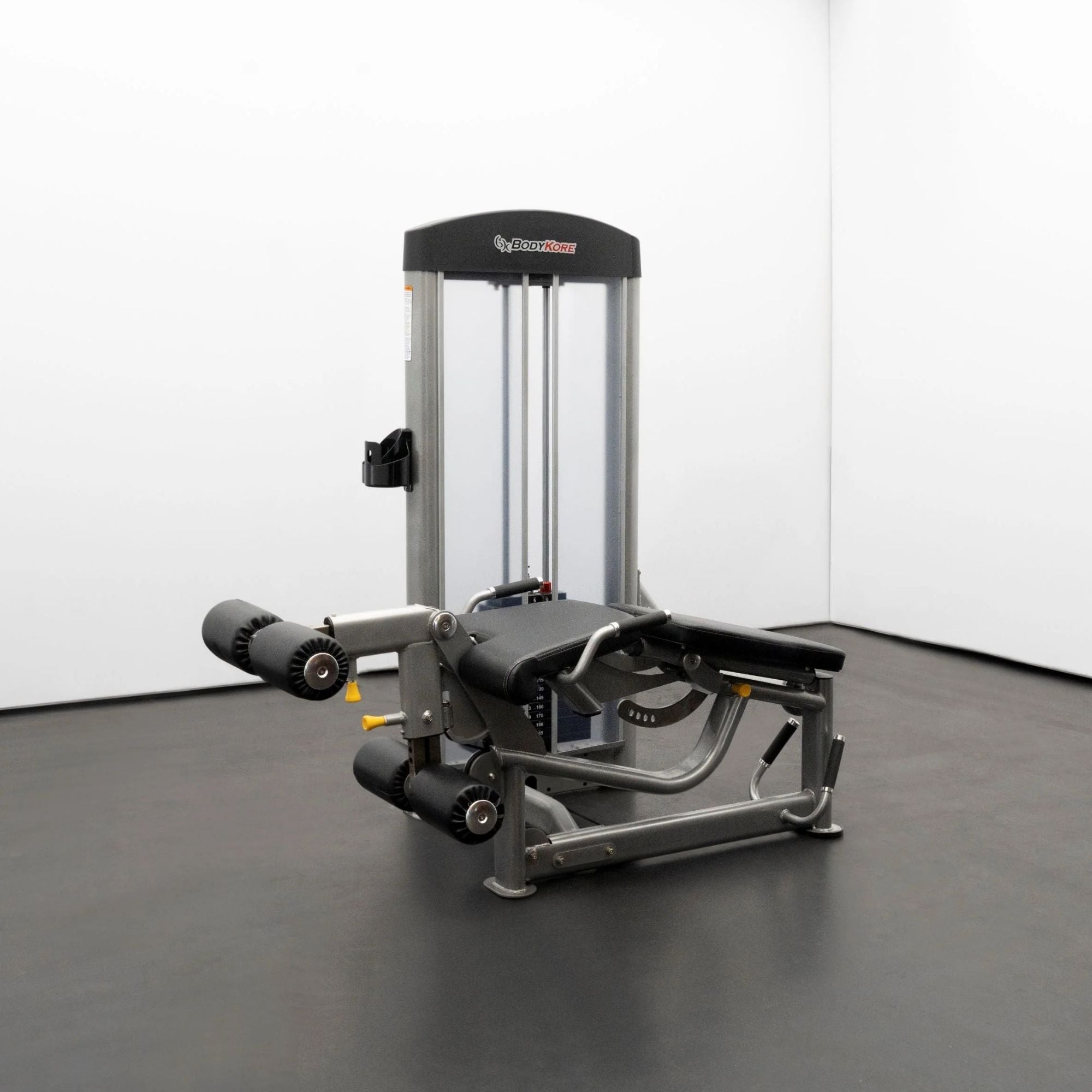 BodyKore Leg Extension/Leg Prone GR643 with black padding, adjustable settings, and a weight stack, displayed in a minimal gym setup.