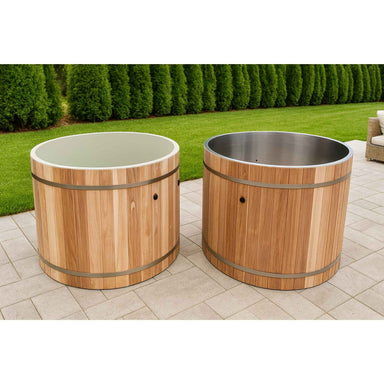 Two wooden barrel-style Dynamic cold plunges on a patio with grass and trees in the background.