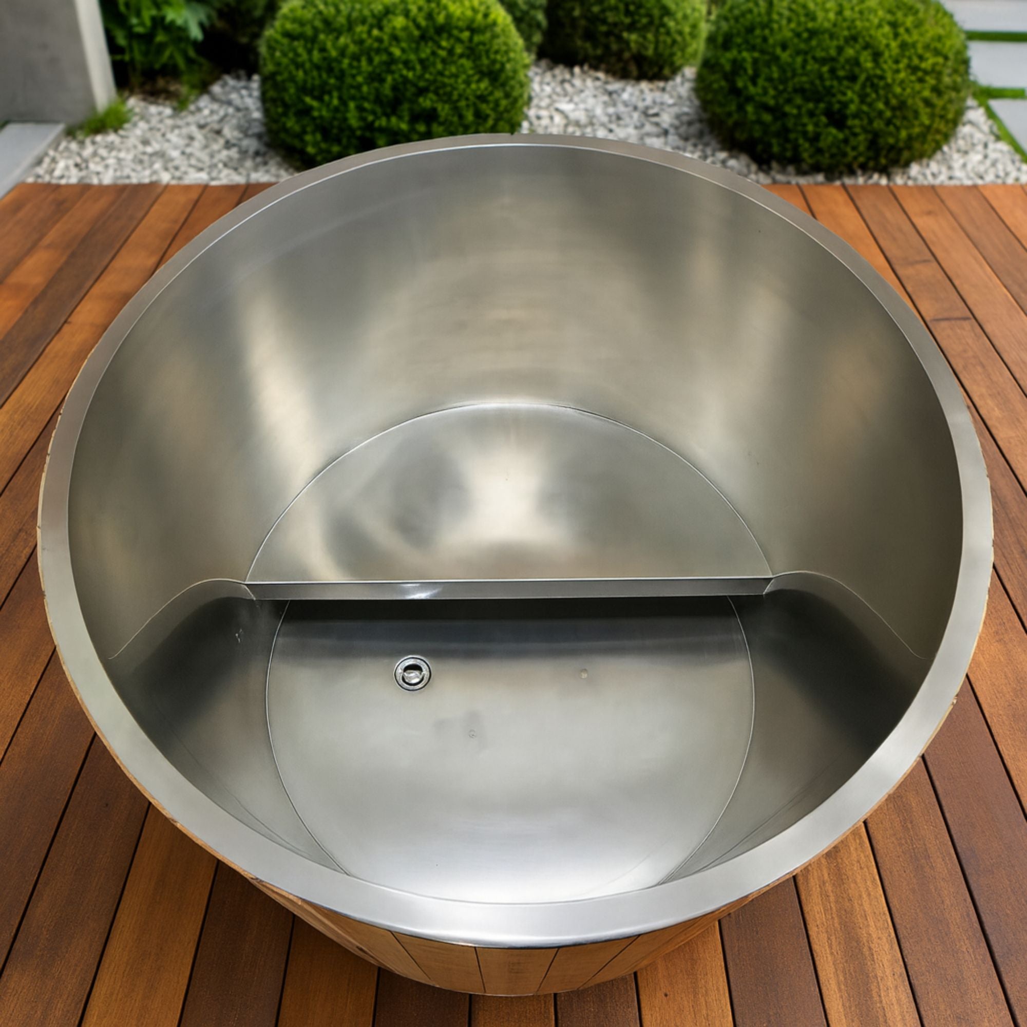 Stainless steel Dynamic cold plunge on a wooden surface with greenery in the background