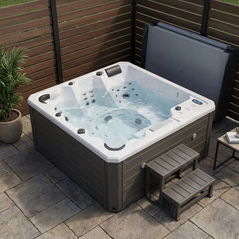 Luxury Spas Galley 5-person Hot tub on a patio with wooden walls and a small table.