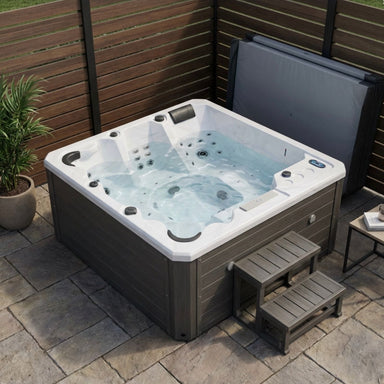 Luxury Spas Galley 5-person Hot tub on a patio with wooden walls and a small table.