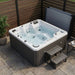 Luxury Spas Galley 5-person Hot tub on a patio with wooden walls and a small table.