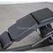 Adjustable weight bench with padded black seat and backrest cushions on a metal frame, photographed in an indoor gym setting.