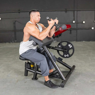 Person using the Muscle D Power Leverage V2 Biceps Curl / Preacher Curl with 45 lb urethane-coated Olympic plates, showing body action shot.