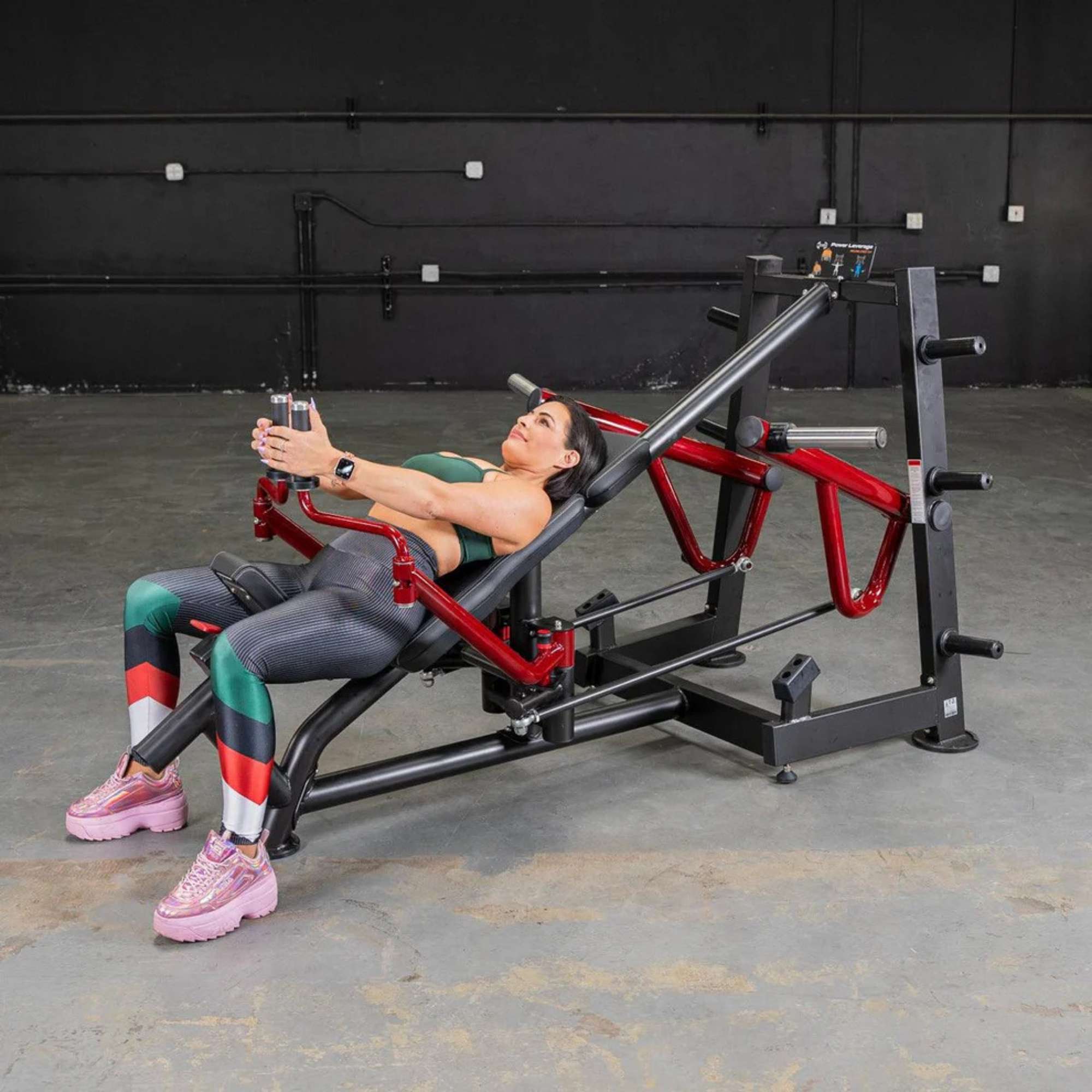 Woman performing chest workout on Muscle D Power Leverage V2 Decline Chest Fly Machine with Olympic weights in a gym setting.