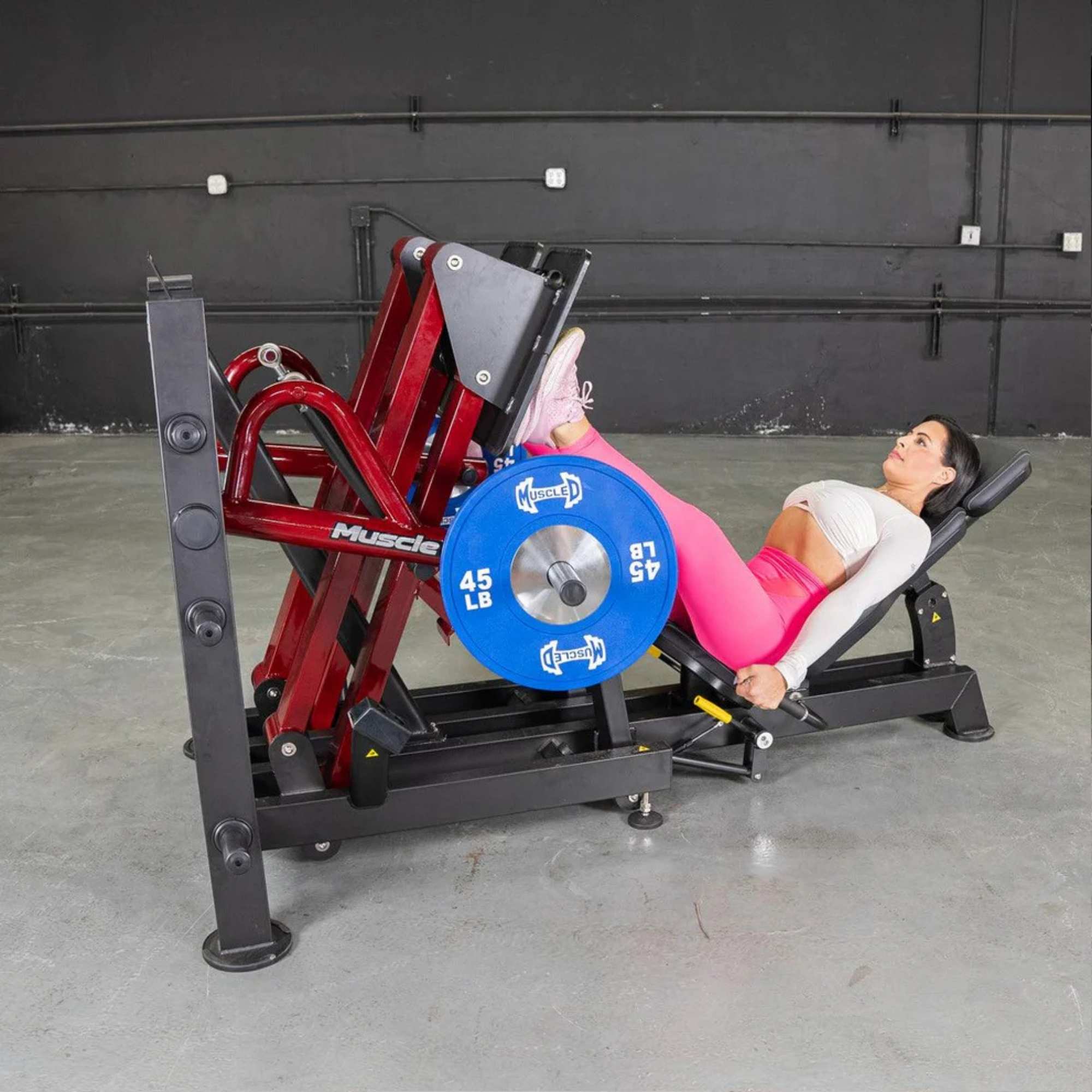 Woman performing a 45-degree leg press on the Muscle D Power Leverage V2, targeting lower body strength and stability.