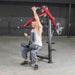 Person using the Muscle D Power Leverage V2 Reverse Grip Lat Pulldown with 45 lb urethane-coated Olympic plates, showing the chest press in action.