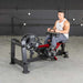 Side view of an athlete performing seated calf raises on the Muscle D Power Leverage V2 Seated Calf Tib PL-PV2-SCT machine.