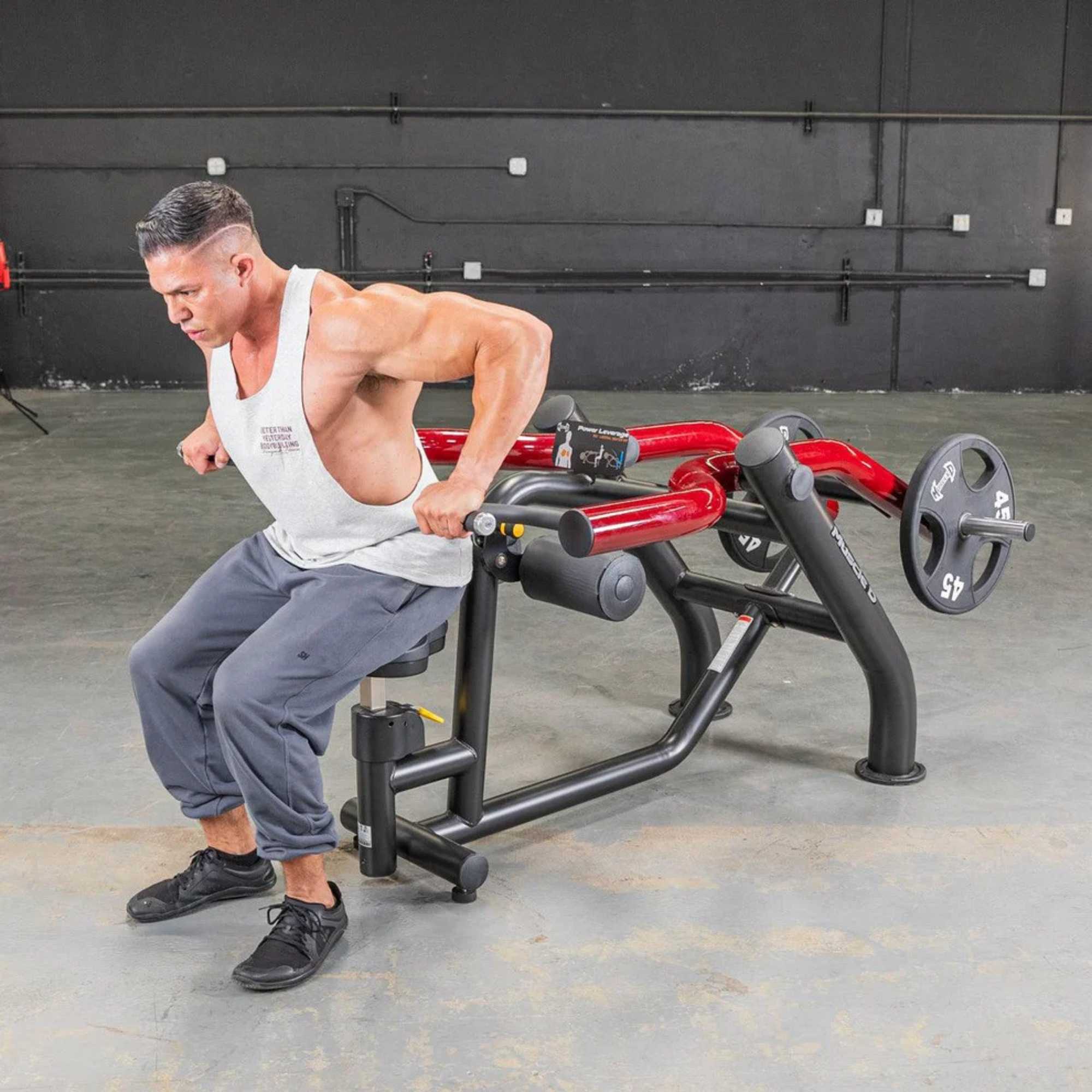 Person using the Muscle D Power Leverage V2 Seated Dip / Triceps Press  with 45 lb urethane-coated Olympic plates, showing a full body action shot.