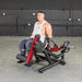 Person using the Muscle D Power Leverage V2 Seated Leg Extension / Prone Leg Curl Combo PL-PV2-LELC with 25 lb Olympic plates, showing the Leg in action shot.