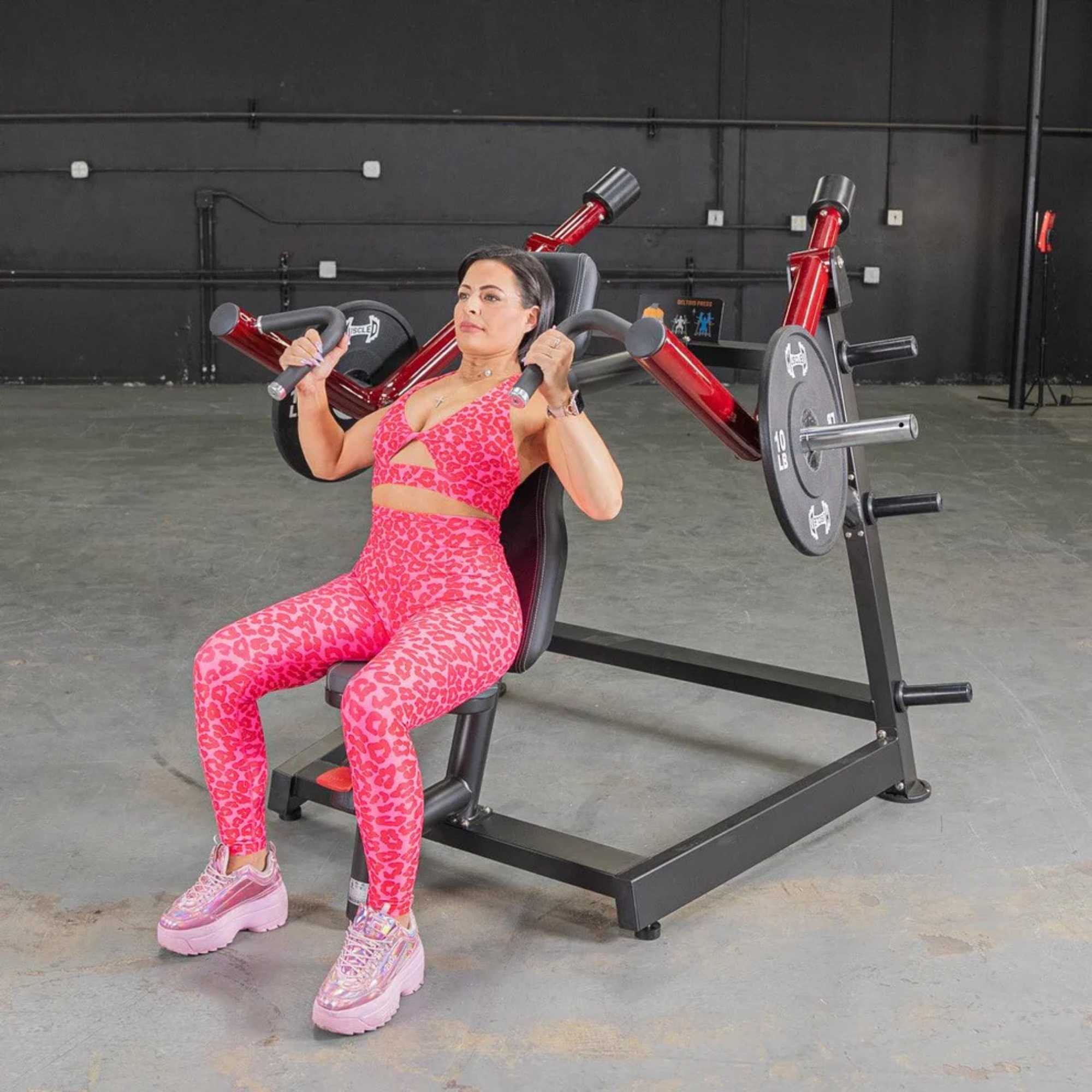 Person using the Muscle D Power Leverage V2 Shoulder Press with 10 lb urethane-coated Olympic plates, showing the Shoulder press in action.