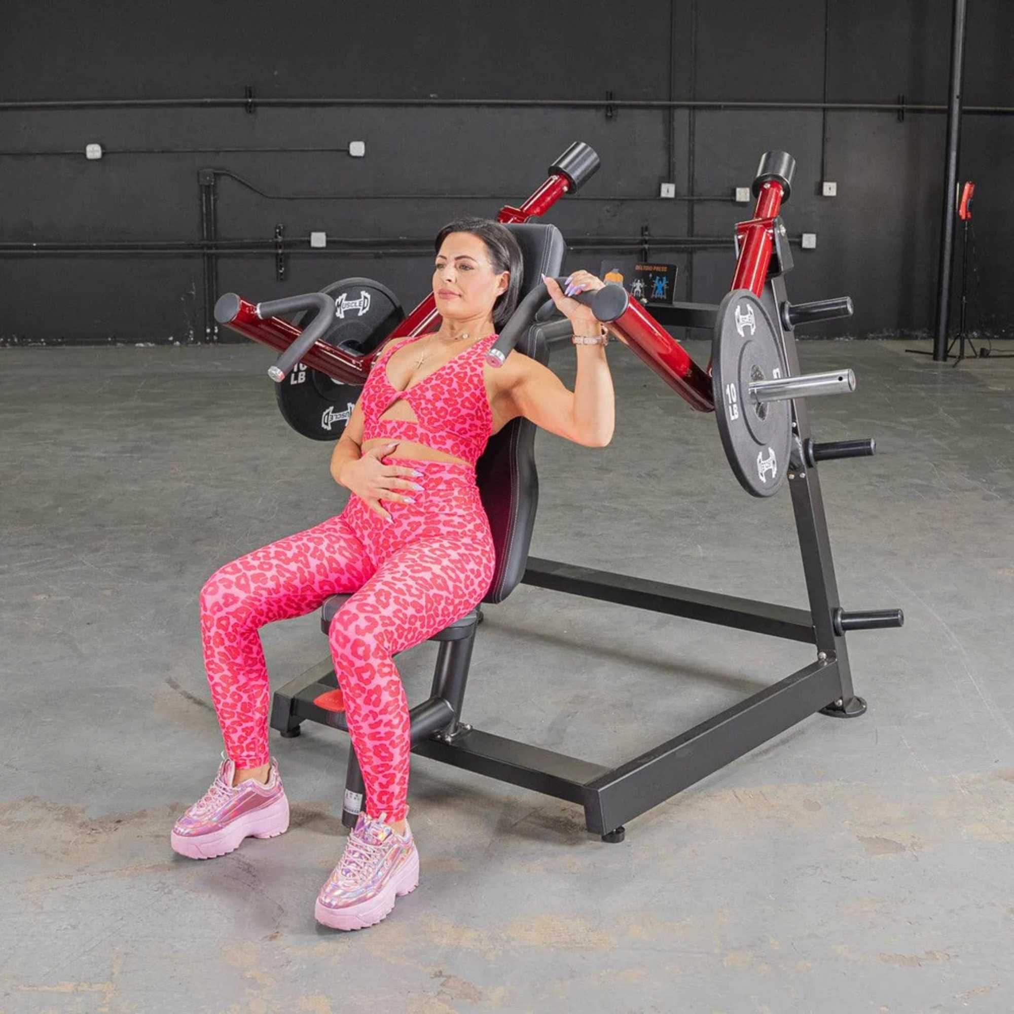 Woman performing shoulder press on Muscle D Power Leverage machine.