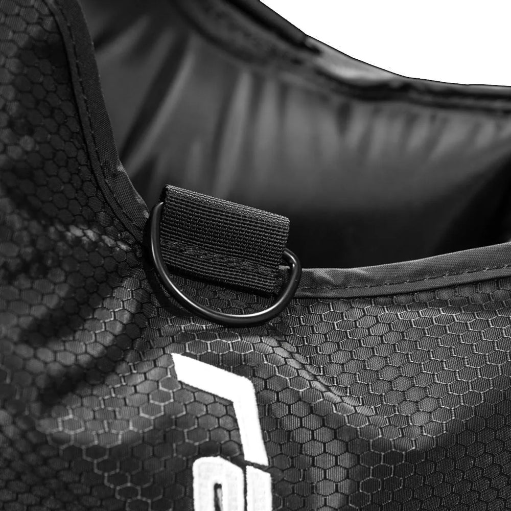 Close-up of a black bag with a D-ring and hexagonal pattern, featuring a brand logo.