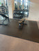 Shok Loks gym flooring with a black adjustable weight bench with a beige seat cushion, positioned on a dark floor mat inside a gym with weight racks and mirrors visible in the background.