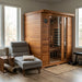 SunRay-3-Person-Savannah-Sauna-HL300K in a room with a gray chair and windows.