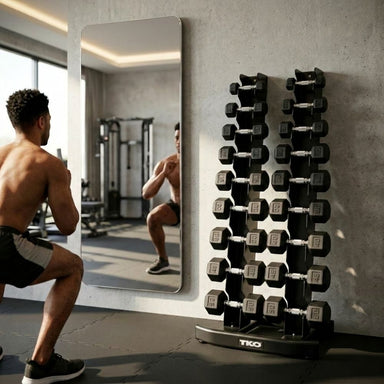Man exercising in a gym with a mirror and TKO Rubber Hex Dumbbell 5-50 lb Set, Straight Handle 804SXR on TKO 10 Pair Vertical Dumbbell Rack 840VDR10-BK