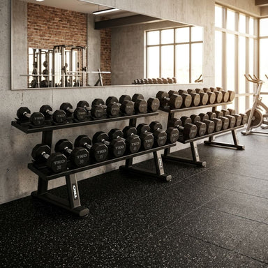 Row of TKO 830TU dumbbells on a TKO 7051B-BK rack in a gym setting with large windows and mirrors.
