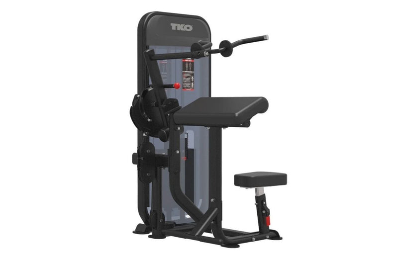A TKO Bicep and Tricep gym machine with a black padded seat and backrest, set against a plain white background.