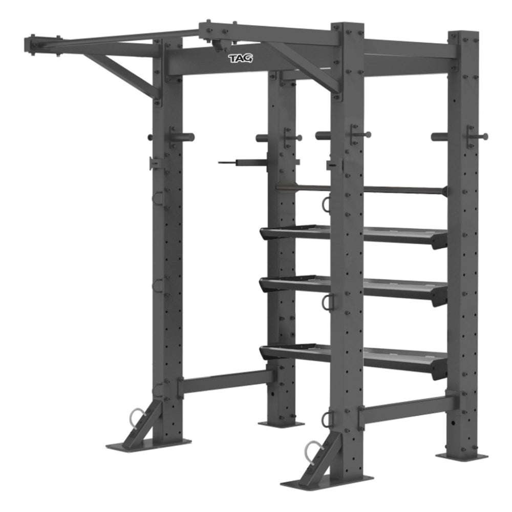 Tag Fitness Free Standing Single Fitness Bay Frame with pull-up bars, storage trays, ball rack, and multiple functional training anchor points. Black metal power rack with multiple shelves and attachments on a white background