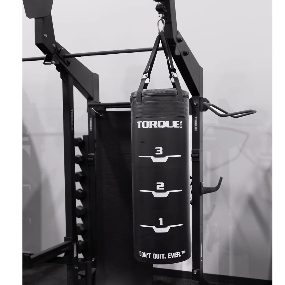 Black punching bag labeled 'Torque' hanging from a gym machine.