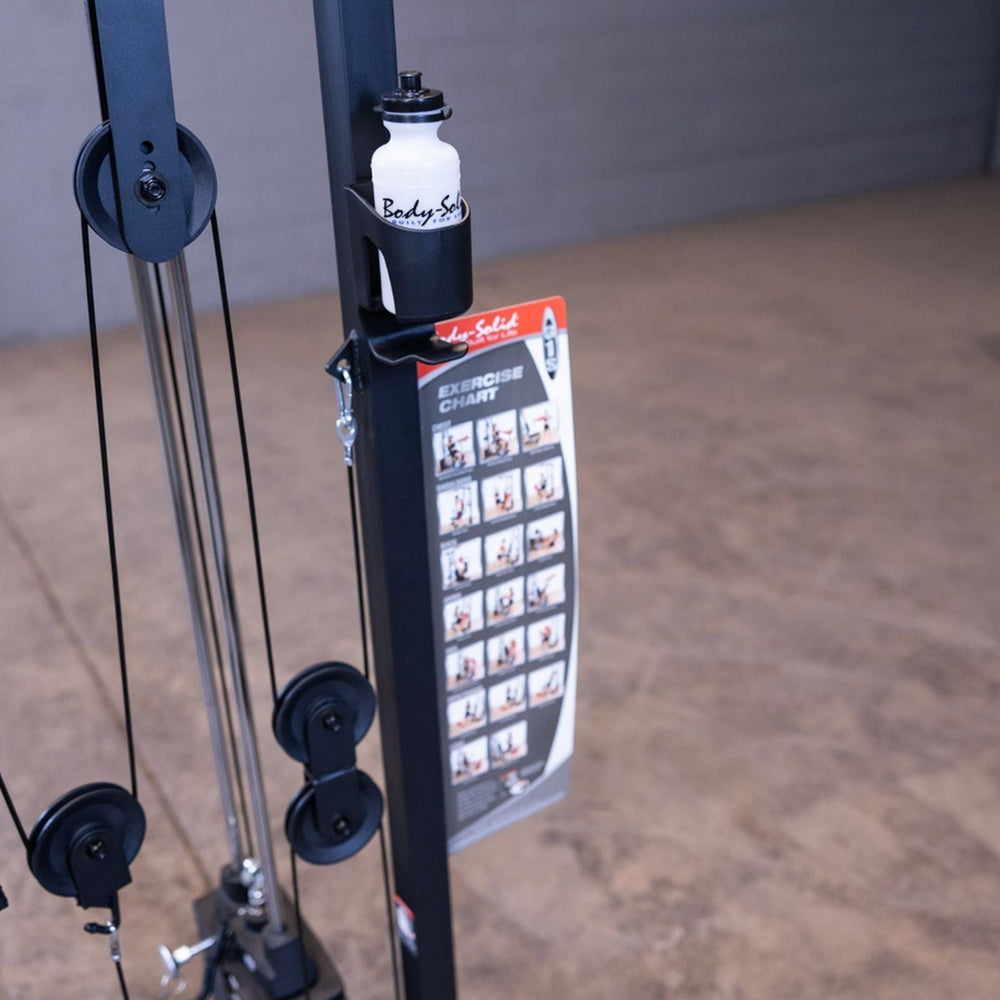 Close-up of the Body-Solid G1S Multi-Station Gym showing the accessory holder with branded water bottle and attached exercise instruction chart
