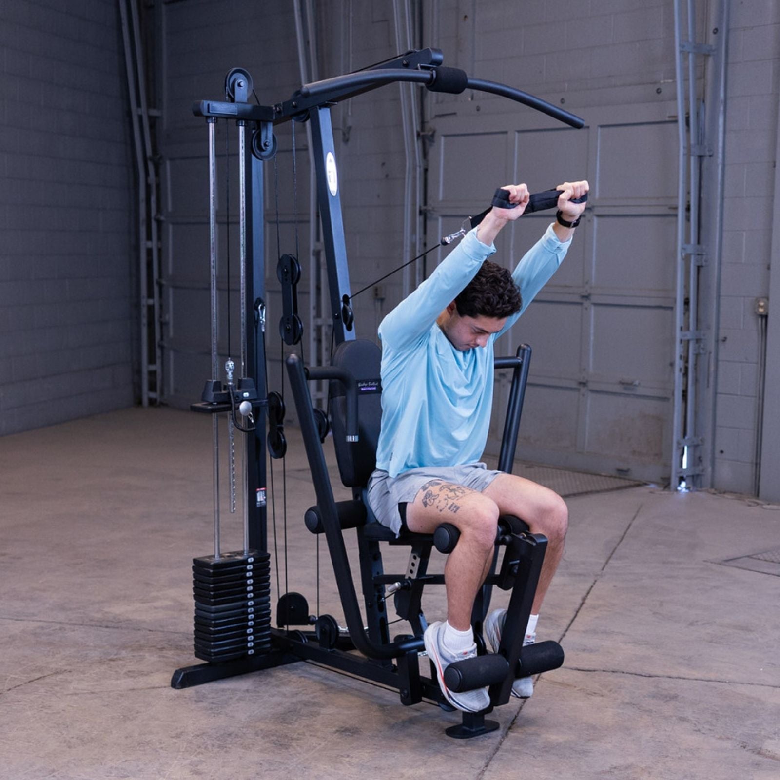 Man performing an ab crunch exercise on the Body-Solid G1S Multi-Station Gym using the mid pulley attachment