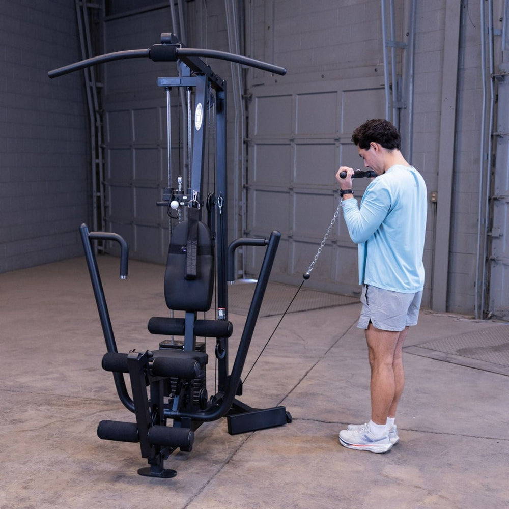Man using the low pulley on the Body-Solid G1S Multi-Station Gym to perform a standing cable bicep curl
