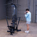 Man using the low pulley on the Body-Solid G1S Multi-Station Gym to perform a standing cable bicep curl