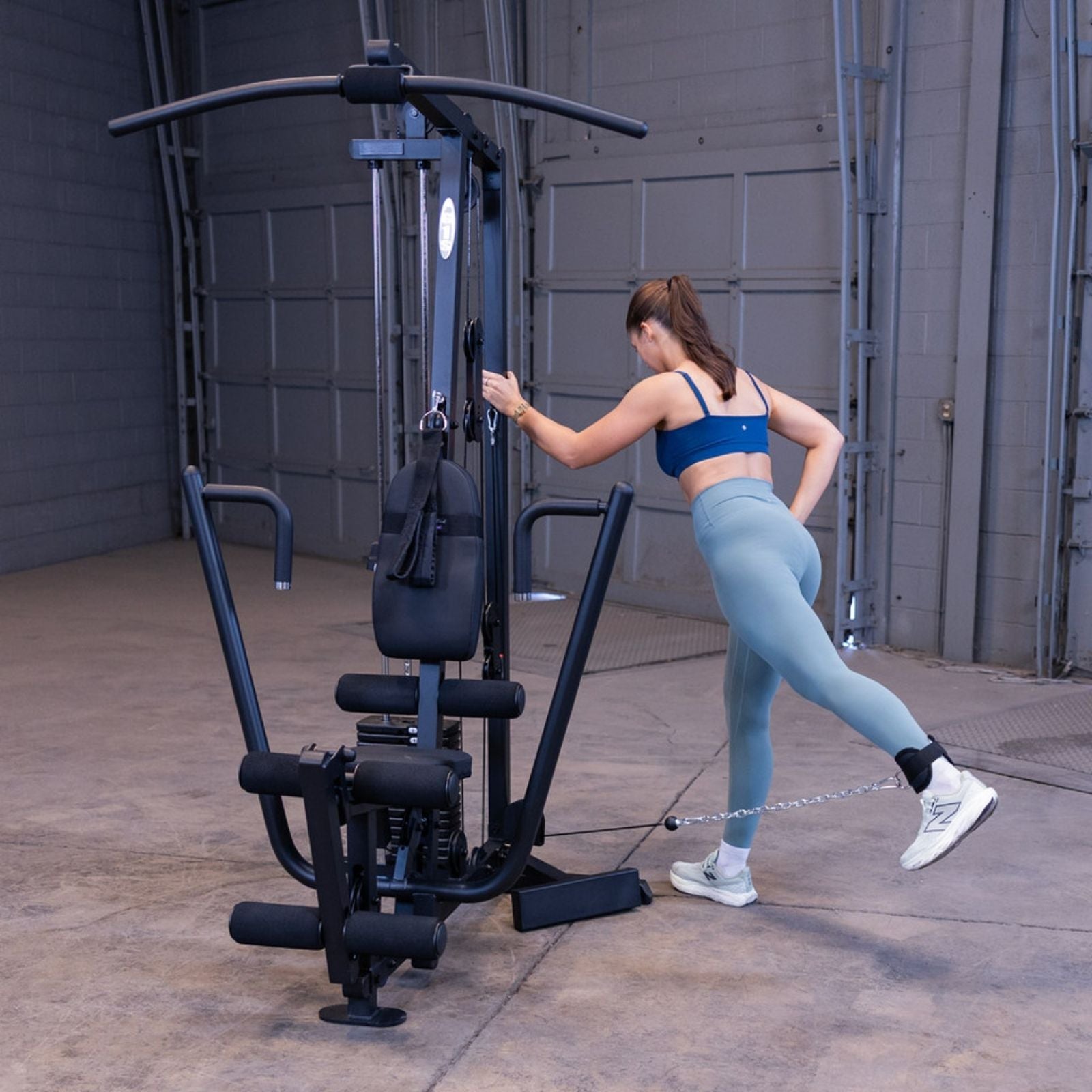 Woman performing a standing cable glute kickback on the Body-Solid G1S Multi-Station Gym using the low pulley and ankle strap