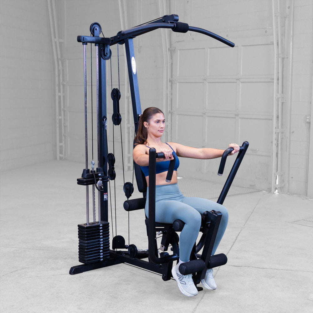 Woman using the Body-Solid G1S Multi-Station Gym performing a chest press exercise in a home gym setting