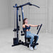 Woman using the Body-Solid G1S Multi-Station Gym performing a chest press exercise in a home gym setting
