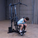 Man performing a high pulley ab crunch using the Body-Solid G1S Multi-Station Gym with ab strap attachment