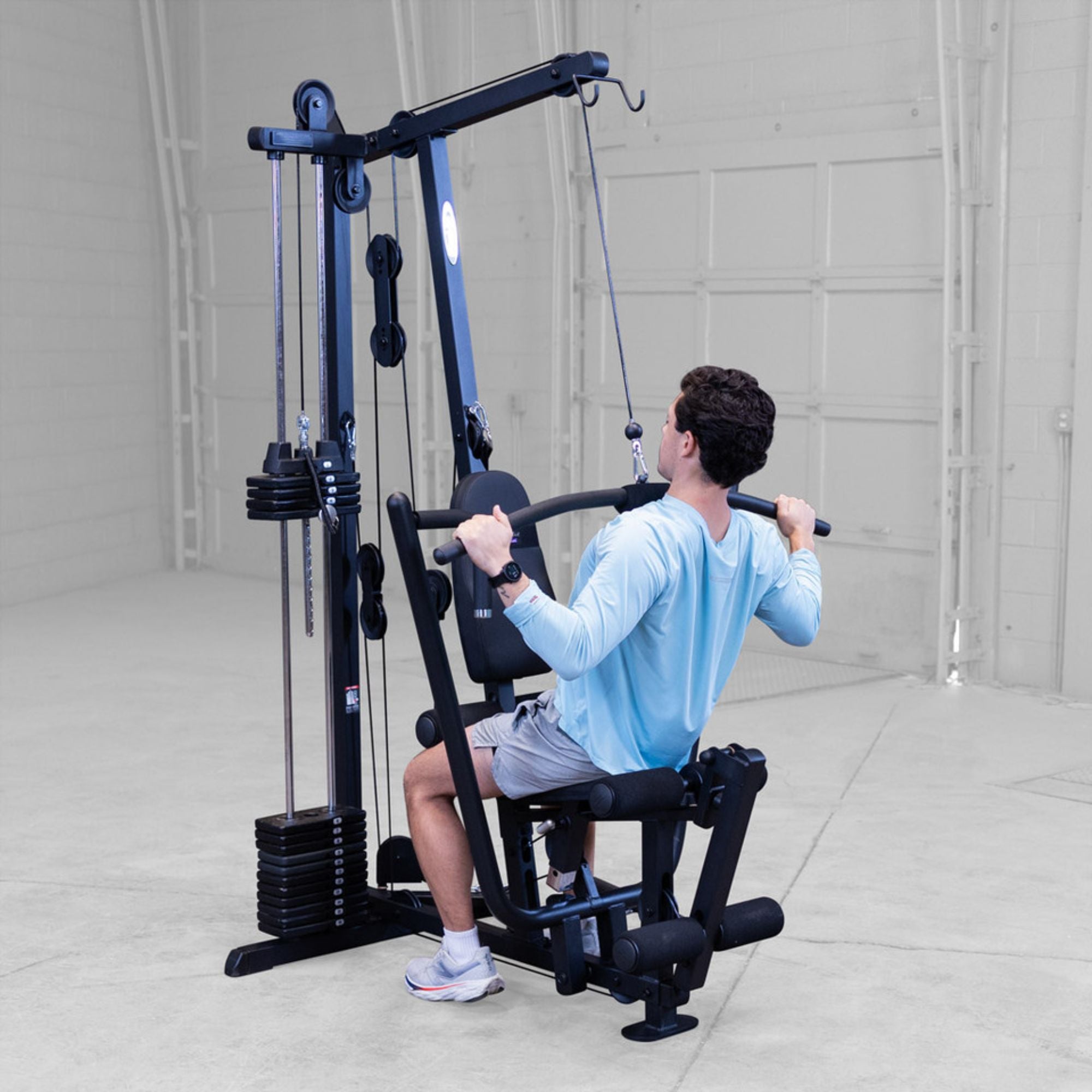 Man using Body-Solid G1S Multi-Station Gym performing a lat pulldown exercise in a home gym setting