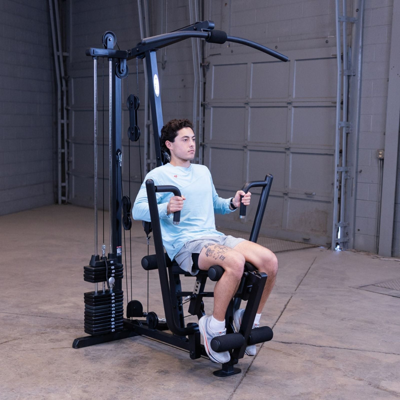 Man performing a seated chest press on the Body-Solid G1S Multi-Station Gym inside a garage gym setting