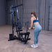 Woman performing a standing triceps pushdown using the high pulley and straight bar on the Body-Solid G1S Multi-Station Gym