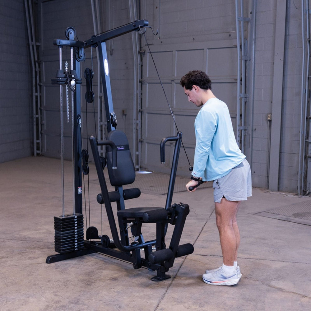Man performing a standing triceps pushdown using the high pulley and straight bar on the Body-Solid G1S Multi-Station Gym