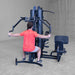 Rear view of Body-Solid G9B dual stack home gym with user performing pec deck chest fly exercise
