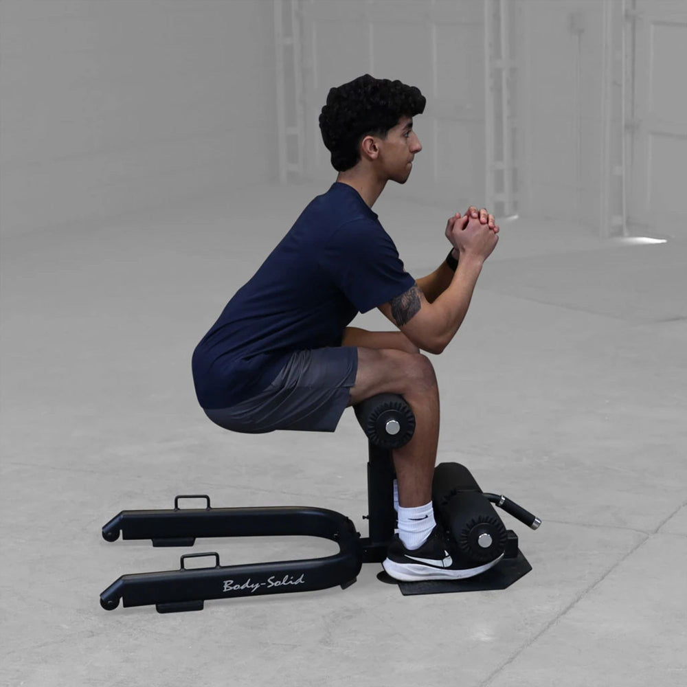 Man using resistance band on Body-Solid GSS50B sissy squat for added quad resistance