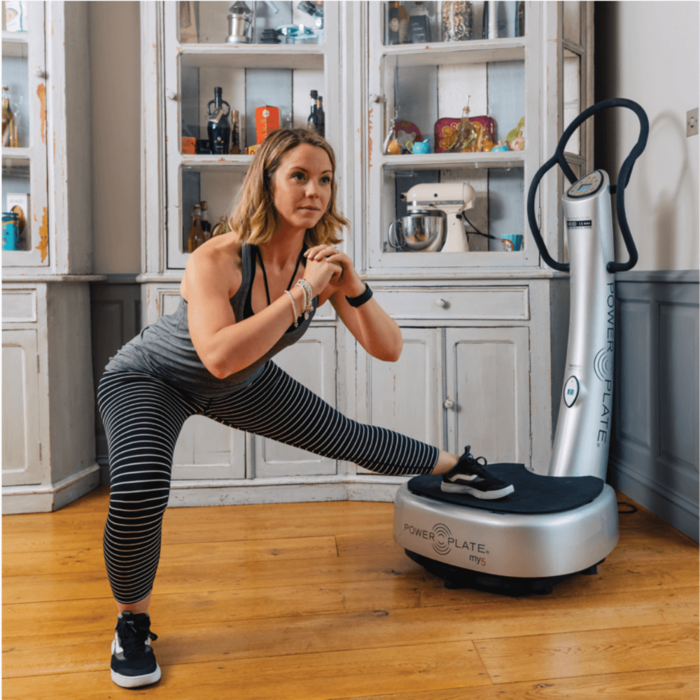 Woman using a Power Plate machine in a kitchen